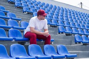 sportsman with a bottle of water sitting and resting at the seats at the stadium photo