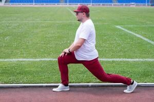 Athletic bearded man warms up before workout at the stadium photo