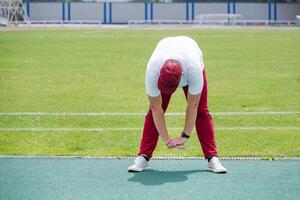 Athletic bearded man warms up before workout at the stadium photo