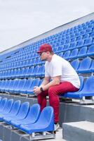 sportsman with a bottle of water sitting and resting at the seats at the stadium photo