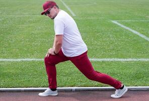 Athletic bearded man warms up before workout at the stadium photo