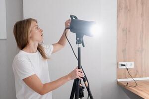 woman maker at work, working on content making, using and controlling light strobe photo