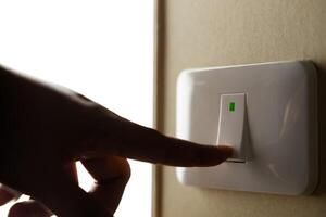Closeup of a Hand Turning Off the Light, Pushing the Switch Off. Climate Resilience Concept, Mitigration, Environmental Care. Saving Energy photo