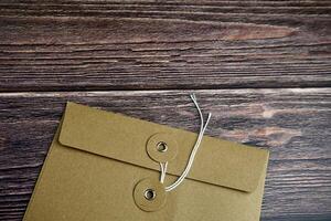 Cropped brown envelope with opened thread lock position isolated on horizontal ratio brown surface table background. photo
