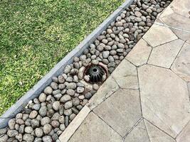 Park pavement ground stone flooring with green grass and metal iron drainage water hole isolated on horizontal ratio outdoor environment background. photo