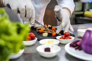 Person Cutting Vegetables on a Cutting Board With White Gloves photo