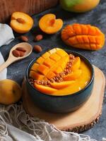 Smoothie bowl topping with fresh mango, peach and granola. photo