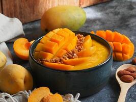 Smoothie bowl topping with fresh mango, peach and granola. photo