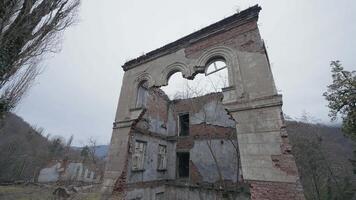 Ruined old building in forest. Action. View of ruined walls of brick building on background of forest. Destroyed houses in gloomy overcast forest video