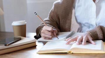 Asian students study online, take notes, do homework, study online from home on a wooden table in the house. photo