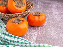 Top view of persimmons with cloth on a wooden table with copy space for text. Concept of health fruit photo