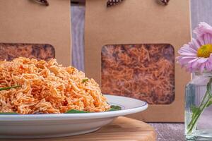 Sweet and sour crispy noodles or Mee krob in the Thai language on a dish with cloth, vase placed on a gray stone background. Side view with copy space for text photo