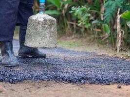 Man holding a cement rod for hammering to adjust the asphalt surface for the walkway. Close-up photo. Constructed from asphalt. Space for text photo