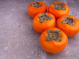 Side view of persimmons on a gray stone background with copy space for text. Concept of health fruit photo