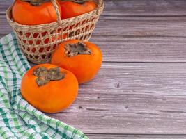 Side view of persimmons with cloth on a wooden table with copy space for text. Concept of health fruit photo