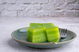 Layer sweet cake and small fork on a plate on gray stone background photo
