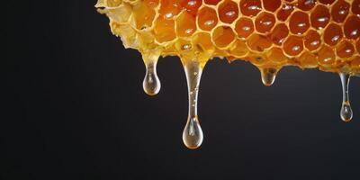 Honey dripping from honeycomb on black background photo