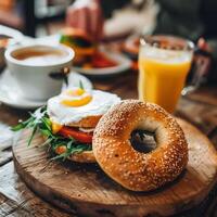 Freshly made bagels with cream cheese, eggs and herbs atop a breakfast table accompanied by refreshing orange juice and coffee photo