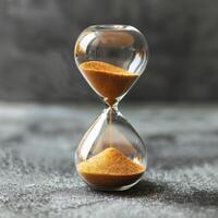 Hourglass. Sand passing in hourglass, countdown running time, deadline on grey background copy space. Falling sand showing the passing time of hourglass close-up and isolated concept for business photo