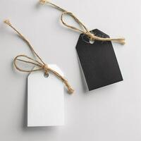 Black and white tags with strings on a gray background, blank tags concept, mock-up, copy space. Label tag mockup. Label Tag mockup template. Cloth label tag blank mockup. Price Label tag mockup. photo