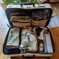 A full packed suitcase assembled for a vacation trip stands on the wooden floor in the room. photo