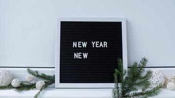 Stop motion animation NEW YEAR NEW ME text on black letter board with cozy minimalistic handmade Christmas decor. New year aims resolutions. Low key festive Planning and setting goals concept video