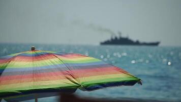Rainbow colored beach umbrellas or parasols against blue sea during a sunny day on a beach. Symbol of vacations, relax, summer. Colorful umbrellas from the sun stand on the beach. Slow motion. video