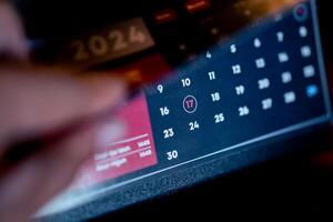 Flipping through a 2024 calendar with a date circled photo