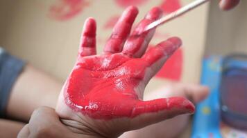 During a creative art session, a childs hand was expertly covered in vibrant red paint video