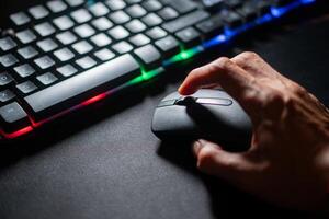 Person using computer mouse with colorful backlit keyboard photo