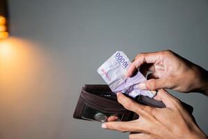 Person holding 10,000 Indonesian Rupiah banknote and wallet photo