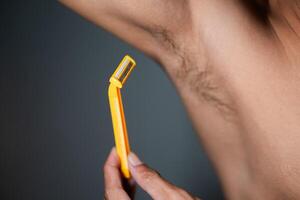 Armpit shaving with yellow razor photo