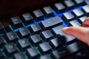 Finger pressing Enter key on backlit mechanical keyboard photo