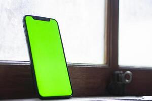Smart phone with green screen by frosted window photo