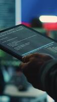 Vertical Person uses tablet in governmental cyber security room working under the Russian flag. Making cyber threats, hacking systems to gain unauthorized access, and spreading fake news. Close up. Camera A. video