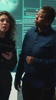 Vertical Cyber security experts women working on spyware and malware detection in a governmental agency. Examining server information on a big screen to combat cyberterrorism and cyberwarfare. Camera A. video
