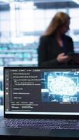 Vertical Laptop in data center establishment with artificial intelligence computing simulating human brain. Close up shot of notebook displaying AI machine learning algorithms, camera B video