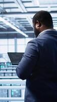 Vertical IT operator in server room workspace using tablet to patch network issues affecting transfer rates. Engineer in data center fixing errors affecting server rows rigs, camera B video