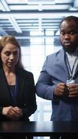 Vertical System administrators looking at holograms in data center, doing swiping motions hand gestures. Server farm workplace employees interacting with augmented reality tech, camera B video