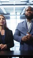 Vertical Admin and coworker looking at holograms in data center, doing swiping motions hand gestures. IT support staff members interacting with augmented reality AI visualization in server hub, camera B video