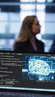 Vertical Close up of laptop with AI technology used to sustain data center hardware. Focus on notebook used by server room programmers in background using artificial intelligence tech, camera A video