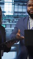 Vertical Teamworking colleagues doing checkup, inputting data on laptop of needed server hub fixes. Coworkers working together in data center housing advanced storage infrastructure, camera A video