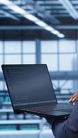 Vertical African american admin in data center running error checking utilities on tablet to fix hardware bugs. IT expert in server hub workspace looking for issues affecting mainframes performance, camera A video