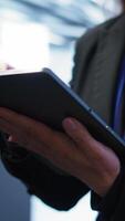 Vertikale Programmierer Verwaltung Daten Center mit fortgeschritten Technologie mit Digital Gerät. schließen oben Schuss von Frau Gehen im Server Zimmer, optimieren Daten Center Technik mit Tablette, Kamera b video