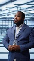 Vertical System administrator looking at holograms in data center, monitoring equipment. Employee in server farm interacting with futuristic augmented reality AI visualization, camera B video
