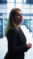 Vertical Engineer walking in data center workspace, monitoring systems to identify root cause of errors. Woman in server hub establishment doing diagnosis, looking for equipment bugs needing repairs, camera B video