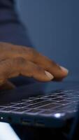 Vertical IT technician working on notebook in data center, overseeing server operations. Extreme close up shot of man ensuring optimal performance and data integrity in server hub, camera A video