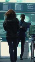 Vertical Group of governmental hackers analyzing digital threats on pc networks, using a big screen. Specialists working on collecting information, fighting against cybercrime and cyberterrorism. Camera B. video
