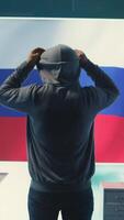 Vertical Russian hacker with a hood installing panic by misconception and manipulation, working in governmental cyber operations room. Impact of fake news and ideology propaganda in a hybrid war. Camera B. video