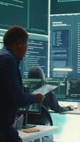Vertical Governmental hackers exploiting network systems in high tech office, executing cyber operations for national server security. Focus on data protection and online safety to combat cybercrime. Camera B. video
